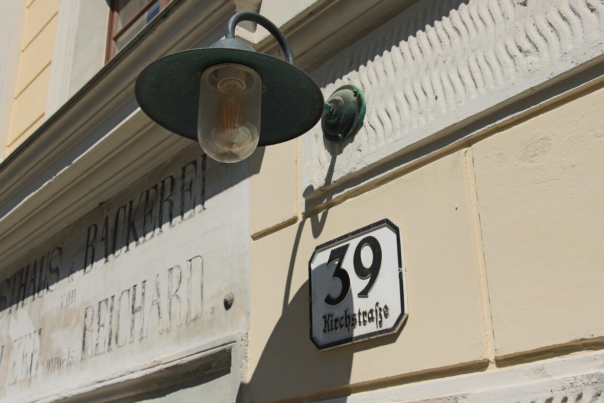 Übermalte Inschrift an der Fassade: Gasthaus und Bäckerei, vormals Reichard, daneben das Emailschild mit der Hausnummer 39 Kirchstraße